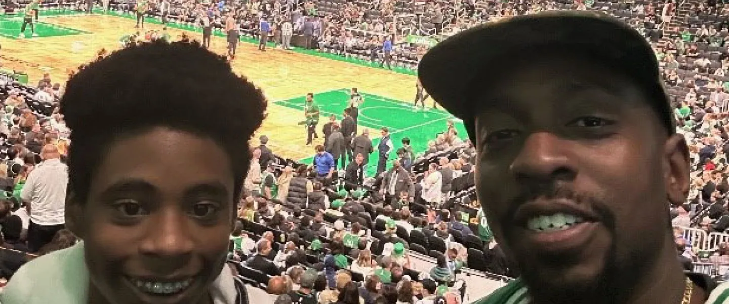 Kid smiling with their mentor at a Celtics game - Mentoring