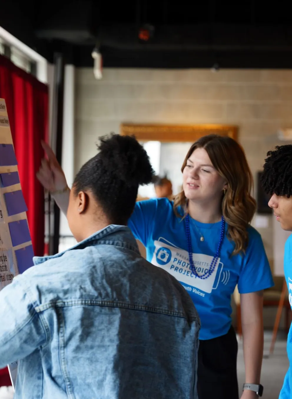 Teens looking as a poster, "What are the Odds" on display at a photo voice event