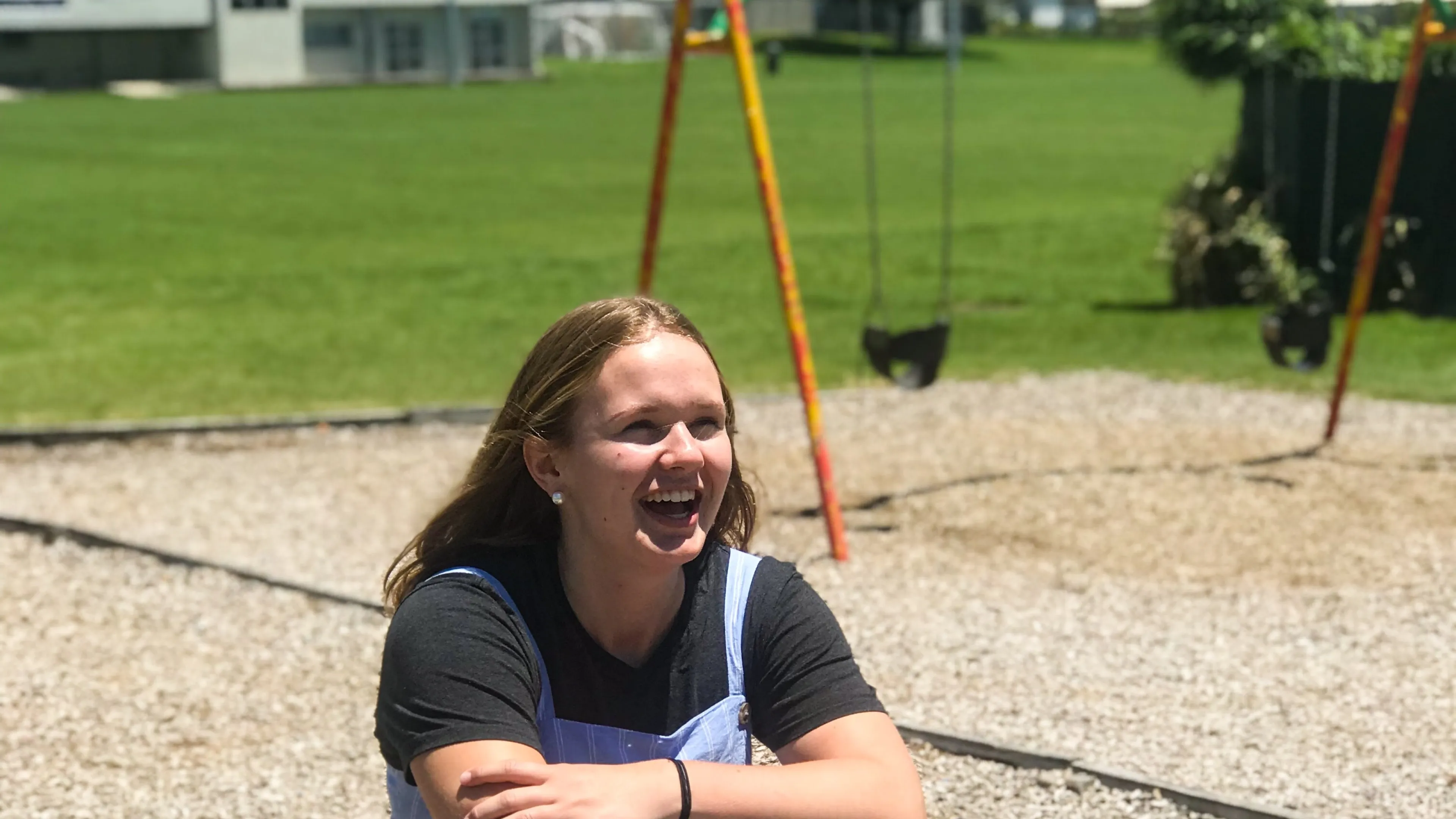 Smiling teenage girl sitting on a teeter totter outside on a playground