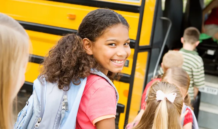 Students boarding a school bus wearing backpacks