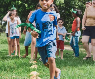 Group of kids outside running in the green grass smiling