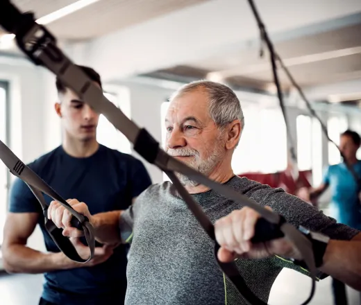 Older gentleman working out with supervision from a certified personal trainer