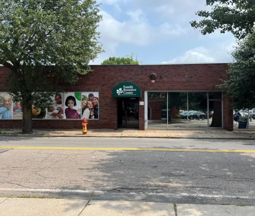 Street view of the Attleboro Family Resource Center brick building with a green awning and decal windows