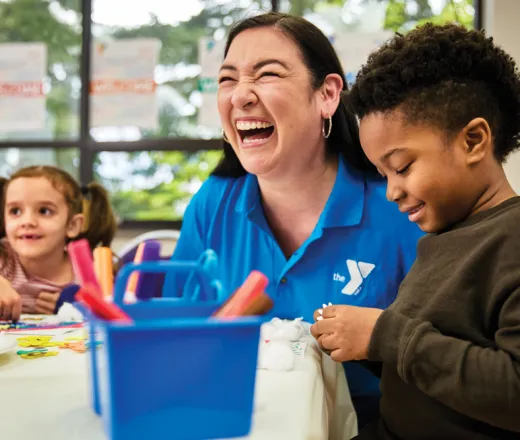 Adult sitting with children laughing while helping with afterschool activities